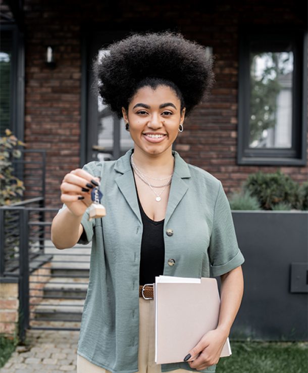 happy and successful african american real estate broker with folder holding key near new cottage